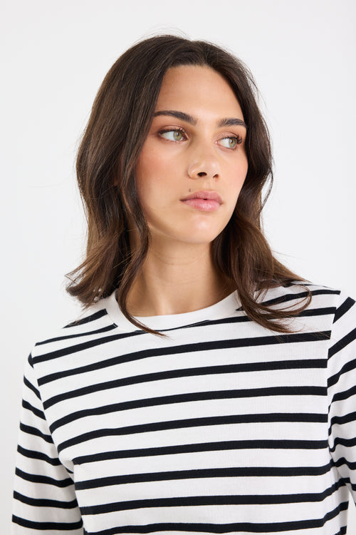 Woman wearing a black and white striped shirt against a plain background
