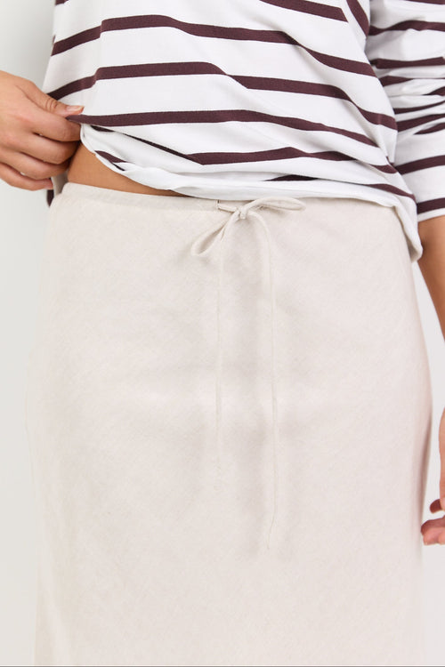 Person wearing a striped shirt and beige pants on a white background
