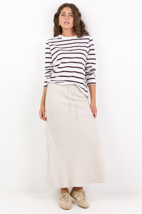 Woman wearing a black and white striped sweater and white skirt on a white background