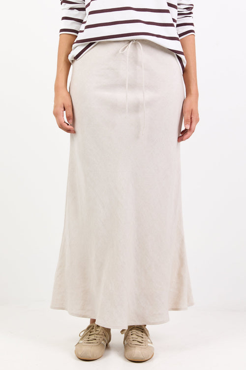Person wearing a striped shirt and beige skirt on a white background