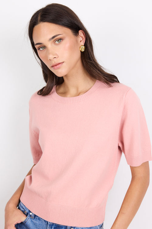 Woman wearing a pink sweater against a white background