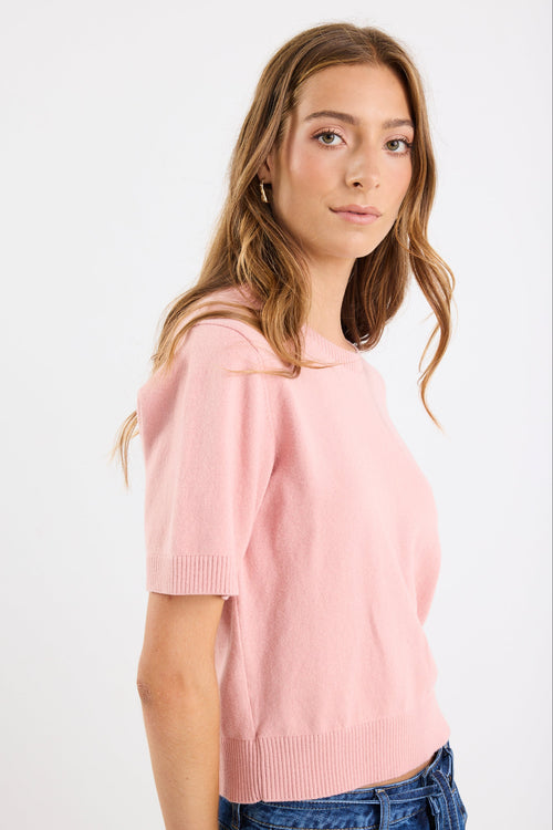 Woman wearing a pink sweater against a white background