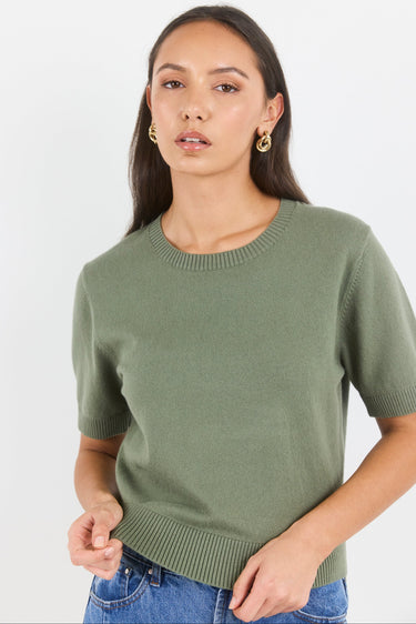 Woman wearing a green sweater against a white background