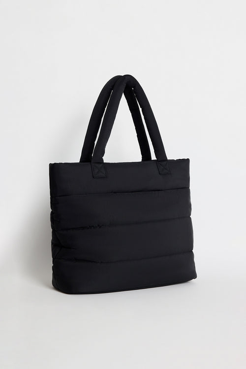 Black quilted tote bag with padded handles, photographed standing upright against a light background.