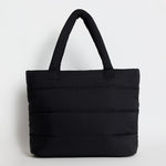 Black quilted tote bag with padded handles, photographed standing upright against a light background.