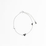 Silver bracelet with heart-shaped charms on a white background