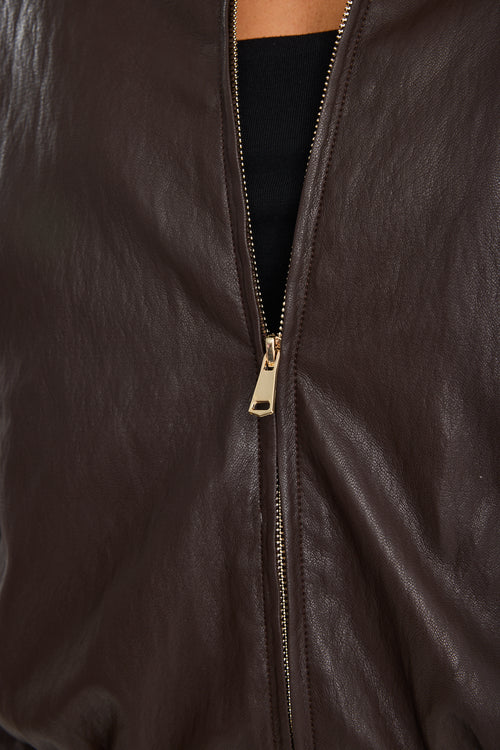 Close-up of a brown leather jacket with a gold zipper.