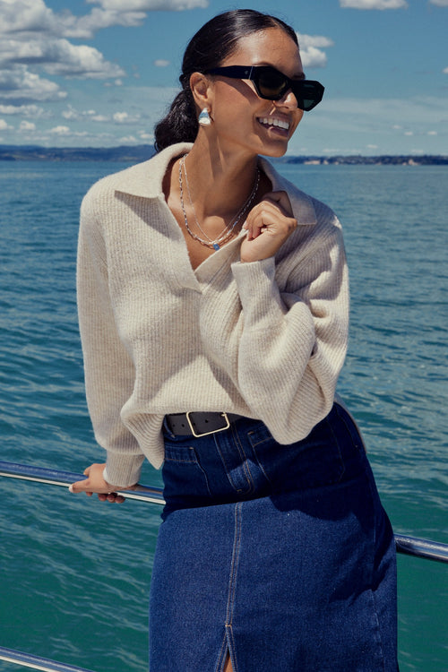 Model wears a beige chunky knit with a denim skirt 