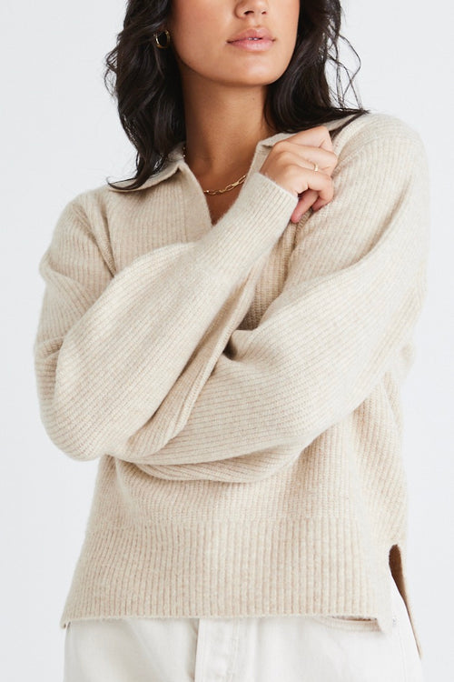 Model wears a beige chunky knit with a denim skirt