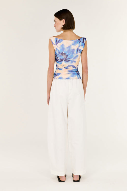 Woman wearing a sleeveless top with a blue and white abstract pattern on a plain background