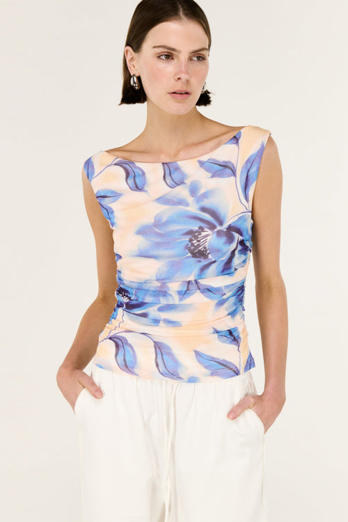 Woman wearing a sleeveless top with blue floral pattern on a white background
