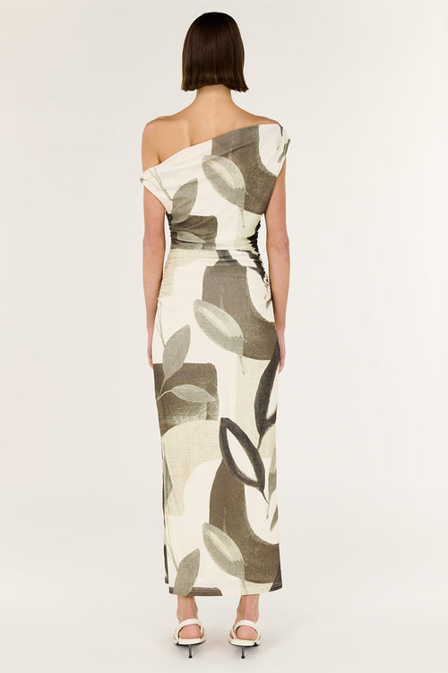 Woman wearing a one-shoulder dress with leaf pattern on a white background