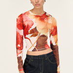 Woman wearing a long-sleeve floral top and black pants on a white background