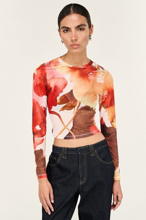 Woman wearing a long-sleeve floral top and black pants on a white background