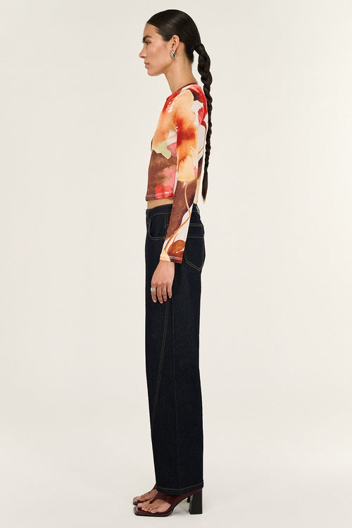 Woman wearing a colorful top and black pants on a white background