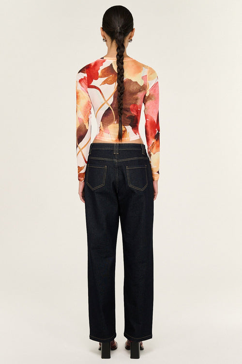 Person wearing a colorful top and black pants on a white background
