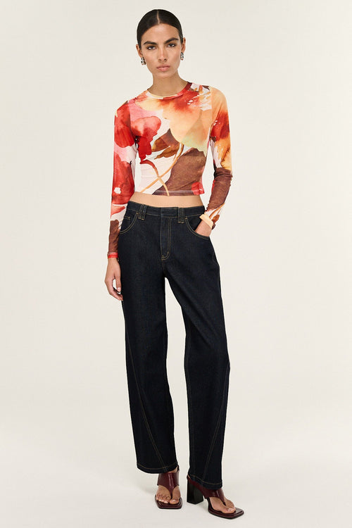 Person wearing a colorful crop top and black pants on a white background