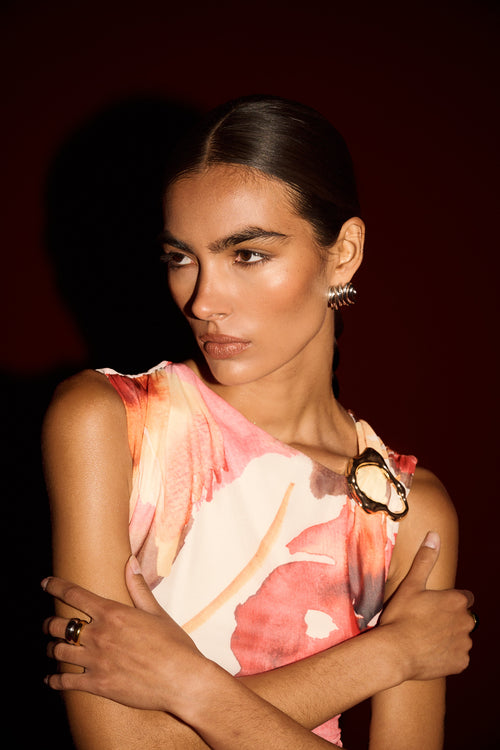 Woman wearing a sleeveless floral top with a dark background