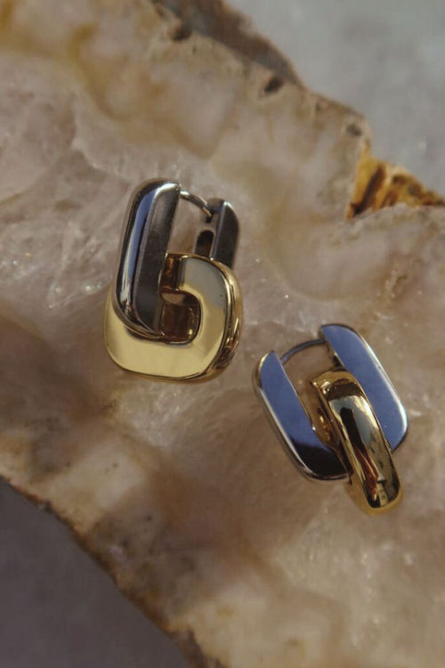 Close-up of U-shaped two tone gold and silver hoop earrings.