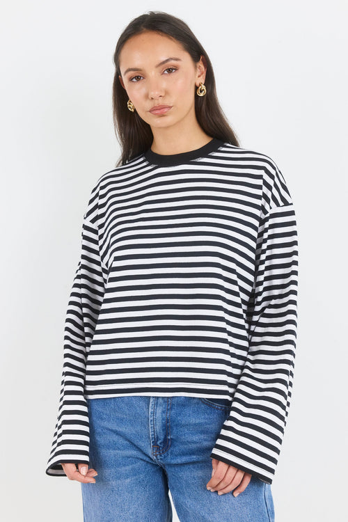 Woman wearing a black and white striped sweater and blue jeans on a white background