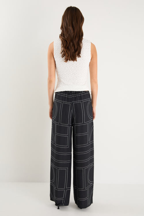 model wears a black wide leg pant with a white tank top