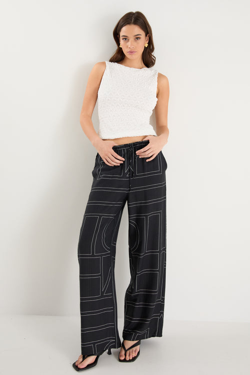model wears a black wide leg pant with a white tank top