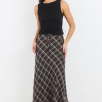 Woman wearing a black sleeveless top and plaid skirt on a white background