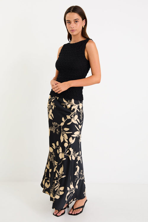 Model wearing a black and beige floral satin bias-cut maxi skirt styled with a black top.