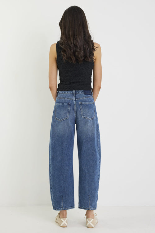 Person wearing blue jeans and a black top on a white background