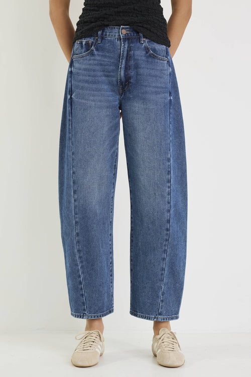 Person wearing blue jeans and beige shoes on a white background