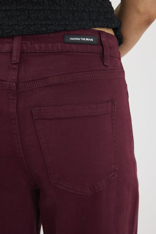 Maroon pants with a brand label on a white background