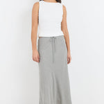 Woman wearing a white sleeveless top and gray skirt on a white background