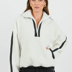 This cozy cream fleece jacket features a zip-up front, sporty black side stripes, and a relaxed fit, paired with black wash jeans for a casual yet stylish look.
