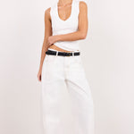 A model wearing a white sleeveless top, white wide-leg jeans with a black belt, black sandals, and sunglasses, standing against a plain white studio background.