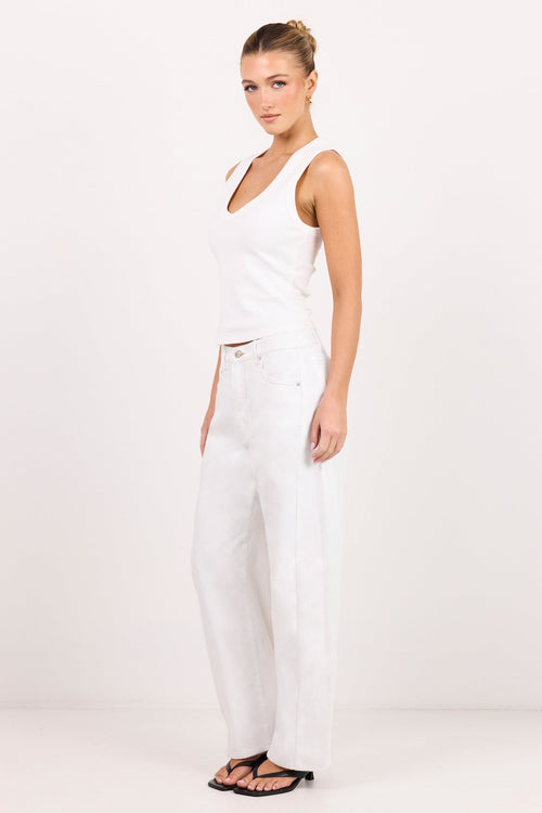 A woman modeling a white sleeveless crop top and matching white wide-leg pants against a plain white studio background.