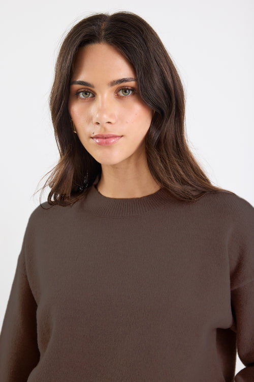 Woman wearing a brown sweater against a white background
