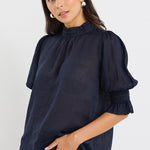 model wears a navy blue blouse with dark blue jeans