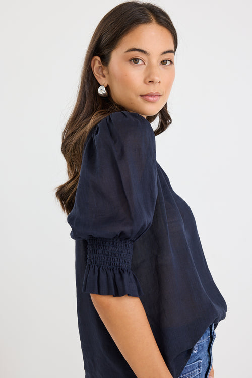 model wears a navy blue blouse with dark blue jeans