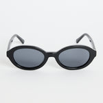 Black oval sunglasses with dark tinted lenses and a glossy frame, photographed against a white background