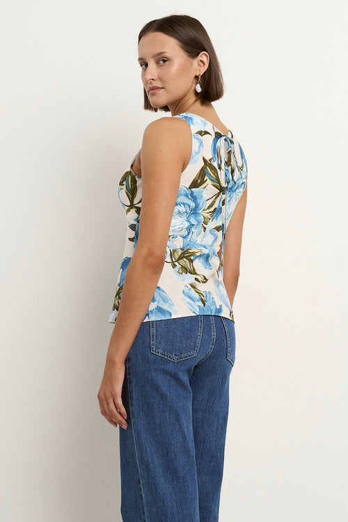 Woman wearing a sleeveless V-neck top with a vintage blue floral print, styled with blue high-waisted jeans.
