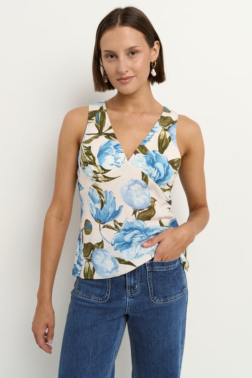Woman wearing a sleeveless V-neck top with a vintage blue floral print, styled with blue high-waisted jeans.
col_pattern