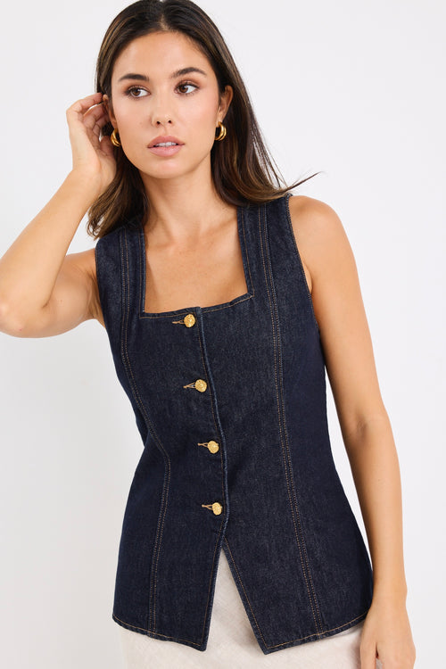 model wears a dark blue denim vest with a beige linen midi skirt