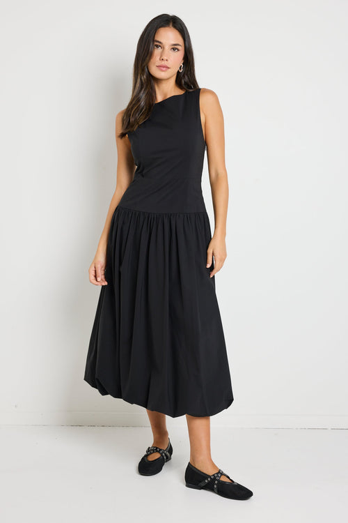 Woman wearing a black bubble hem midi dress, styled with black flats for a playful yet sophisticated look.