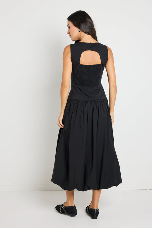 Woman wearing a black bubble hem midi dress, styled with black flats for a playful yet sophisticated look.