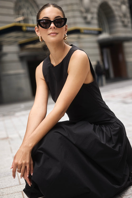 Woman wearing a black bubble hem midi dress, styled with black flats for a playful yet sophisticated look.