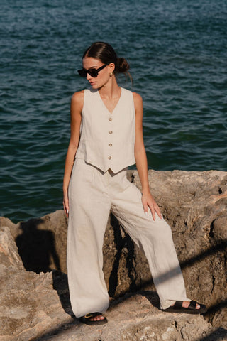 model wears a matching natural linen vest and pants combo at the beach