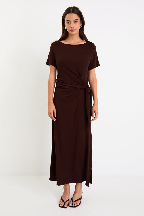 Model wearing a chocolate brown short sleeve jersey maxi dress with a waist tie and side split