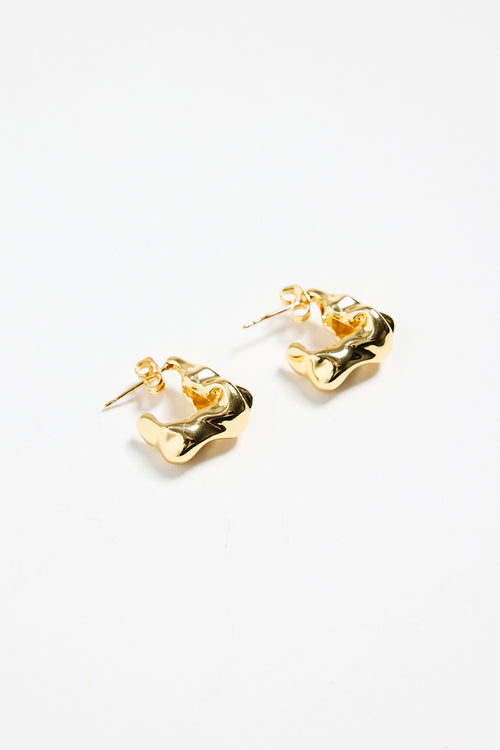 gold-plated brass huggie earrings with a wavy, organic design, photographed flat against a white background.