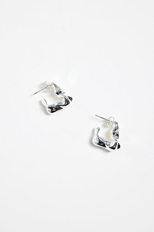 silver-plated brass huggie earrings with a wavy, organic design, photographed flat against a white background.