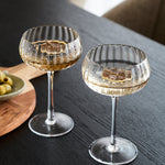 Two clear ribbed-stone wine glasses filled with white wine
